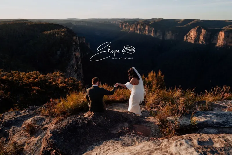 A couple walking along a Blue Mountains clifftop at sunset